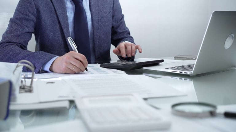 Businessman working with laptop, calculator and documents in professional office
